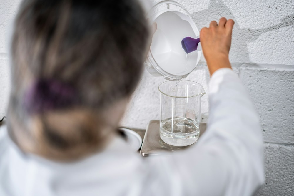 Een laboratoriummedewerker giet een vloeistof in een glazen maatbeker